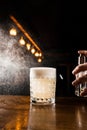 Bartender is spraying whiskey over Penicillin coctail. Alcohol cocktail with whiskey, lemon juice, and honey-ginger