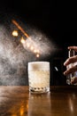 Bartender is spraying whiskey over Penicillin coctail. Alcohol cocktail with whiskey, lemon juice, and honey-ginger