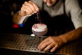 Bartender sprinkling on the cocktail decorated with petals a shredded flowers