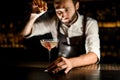 Bartender sprinkling cocktail in glass on a counter