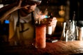 Bartender sprinkling to the red cocktail in the glass with a crushed ice a spices and burning them