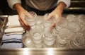 Bartender stacking clean patterned tumblers with towels Royalty Free Stock Photo