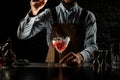 Bartender throwing a red rose bud to a martini glass with a golden cocktail Royalty Free Stock Photo