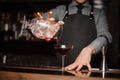 Bartender in a tie and apron pouring red alcoholic drink in a cocktail glass Royalty Free Stock Photo