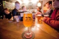 Bartender, visitors drinking craft beer, and glass of danish beer by Mikkeller brewery with design glass