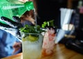 Bartender wearing medical latex black gloves,making mojito cocktail.Process of bartending in bar