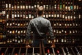 Bartender at wine cellar full of bottles with exquisite drinks