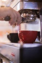 Bartender working on coffee machine in red cup and black cup Royalty Free Stock Photo