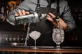 Bartenders hands pouring alcoholic drink into a glass using a jigger to prepare a cocktail Royalty Free Stock Photo