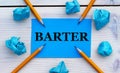 BARTER - word on blue paper on a light background with crumpled pieces of paper and pencils Royalty Free Stock Photo