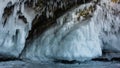 The base of the granite rock is covered with a thick layer of ice, bizarre icicles