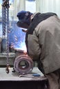 The base for the valve is mounted on the iron table at the factory and the worker welds with a welding machine. Sparks Royalty Free Stock Photo