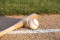 Baseball and bat laying on basepath with grass infield Royalty Free Stock Photo