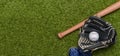 Baseball bat, shoes, glove and ball on green grass field. Sport theme background with copy space for text and advertisment