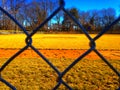 Baseball field view from the dugout through fence Royalty Free Stock Photo