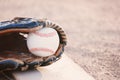 Baseball game shows ball with glove laying on field closuep. Royalty Free Stock Photo