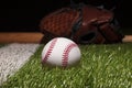 Baseball on grass field low angle close up with mitt and bat soft focus behind Royalty Free Stock Photo