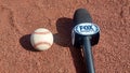 A Major League Baseball on a stadium infield next to a Fox Sports mic