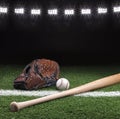 Baseball mitt ball and bat at night under stadium lights Royalty Free Stock Photo