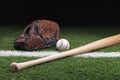 Baseball with mitt and bat on green grass at night Royalty Free Stock Photo