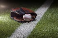 Baseball in a mitt at a low angle on a field with stripe and dramatic lighting and dark background Royalty Free Stock Photo