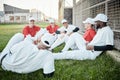 Baseball team, communication and stadium grass with sport group sitting on a fitness break. Training, exercise and Royalty Free Stock Photo