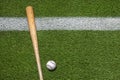 Baseball and wooden bat on grass field with white stripe overhead view Royalty Free Stock Photo