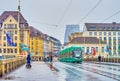 The view on modern green tram ridding on Mittlere Brucke on rainy day in Basel, Switzerland