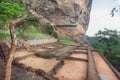 Basement of ancient city palace on Sigiriya rock and tourists walking around archeological area Royalty Free Stock Photo