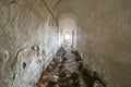 Basement of old fortress building, long narrow corridor with vaulted plastered ceiling and dirty floor