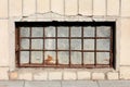 Basement window made of strong frame with metal bars and sheet metal filling mounted on house wall locked with rusted padlock