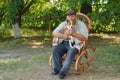 Basenji sitting with master on a wicker chair