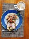 Basic breakfast of a sandwich, scrambled eggs and tomato served on a wooden table top view Royalty Free Stock Photo