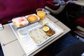 Basic inflight meal consisting rice, egg, beef curry, bread, juice