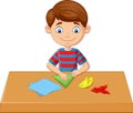 Little boy folding paper and making origami toys