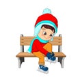 Cute boy in winter clothes sitting on a bench  little boy tying his shoelaces Royalty Free Stock Photo