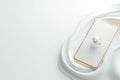 A basic smartphone shape rests on a smooth white surface, featuring a small globe icon that symbolizes connectivity. The