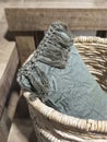 Basic vintage pale green cotton cushion with fringes in a wicker basket. Ethnic and hygge interior decoration. Corner detail of