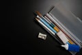 Basic white plastic pencil box with pencil, pen, eraser, sharpener and paintbrush on black background. Royalty Free Stock Photo