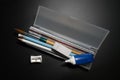 Basic white plastic pencil box with pencil, pen, eraser, sharpener and paintbrush on black background. Royalty Free Stock Photo