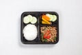 Basil fried rice with minced pork, put in a black plastic box, put on a white tablecloth, food box