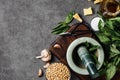 Basil pesto with sauce preparation ingredient on home kitchen table. Top view marble mortar and spices for cooking Royalty Free Stock Photo