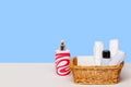 Basket with bath accessories such as soap bars, Cream and cosmetic tissues for body care on a white table over blue background Royalty Free Stock Photo