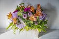 A basket of beautiful colorful spring flowers with a purple organdy ribbon sitting in a ray of sunshine Royalty Free Stock Photo