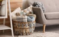 Basket with blankets and pillows near sofa