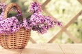 Basket with a bouquet of lilac flowers on a white wooden table in the summerhouse in the garden Royalty Free Stock Photo