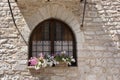 A basket of bright pink and red flowers hangs on the window of a home in an ancient building in Italy Royalty Free Stock Photo