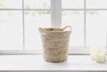 Basket and candles in front of a window shedding light on the interior of boho style living room