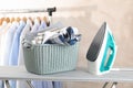 Basket with clean laundry and iron on ironing board Royalty Free Stock Photo