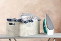 Basket with clean laundry and iron on ironing board Royalty Free Stock Photo